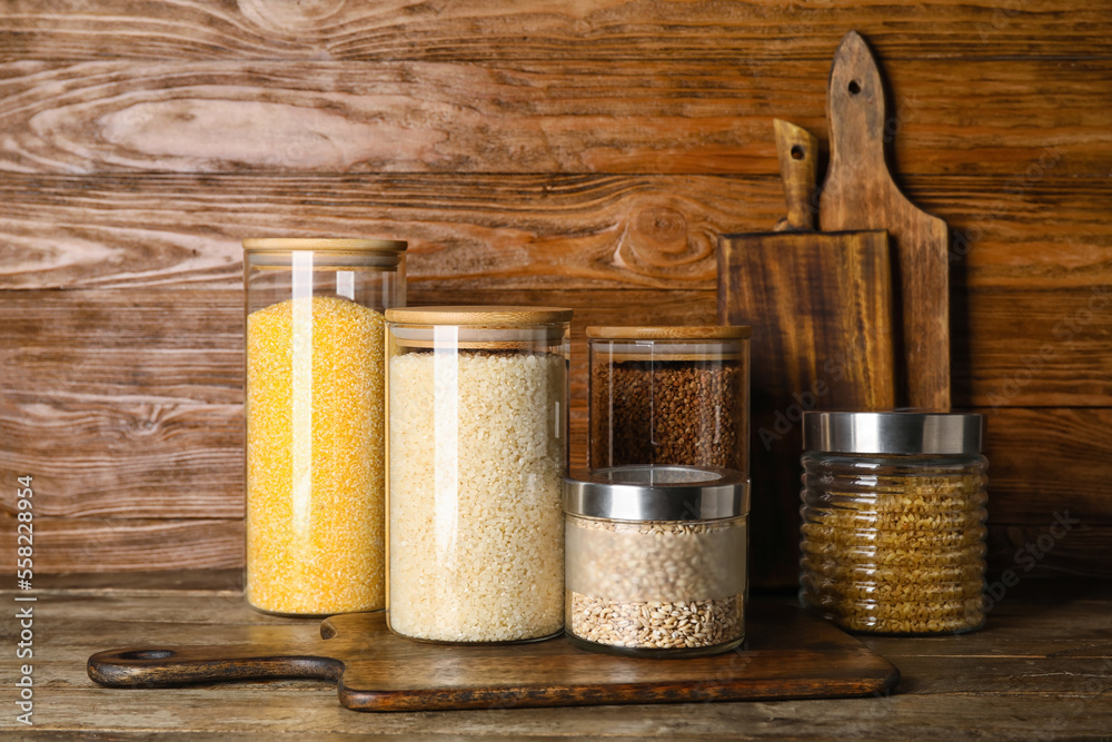 Jars with different cereals on wooden table