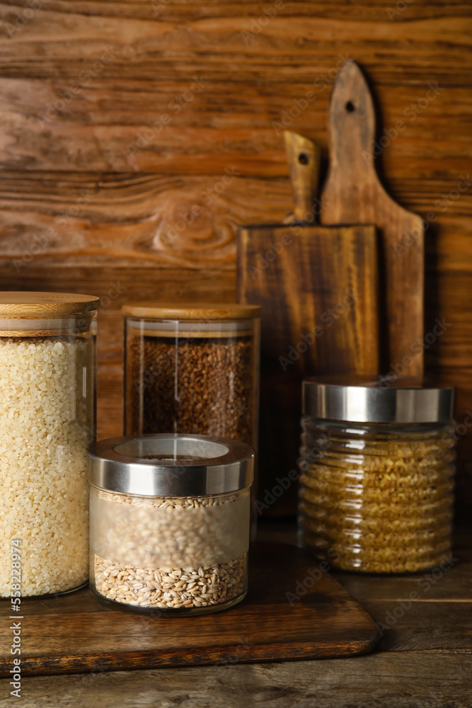 Jars with different cereals on wooden table