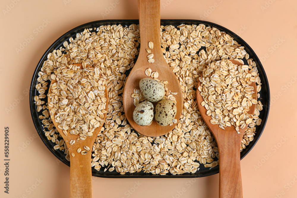 Plate with spoons of raw oatmeal and quail eggs on color background, closeup