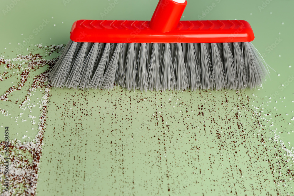 Sweeping of rubbish with broom on color background, closeup