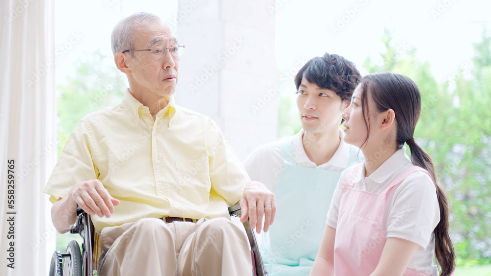 車椅子に乗った高齢者を介護するヘルパー