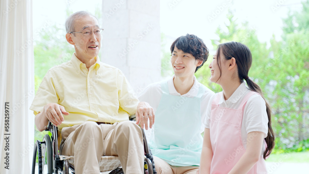 車椅子に乗った高齢者を介護するヘルパー