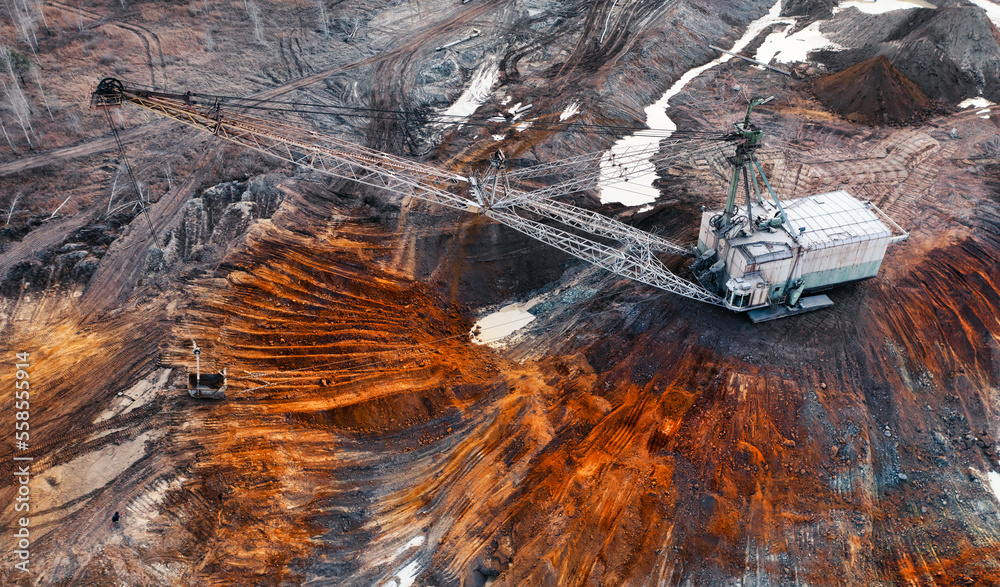 A large walking excavator works in a quarry for the extraction of rare metals.