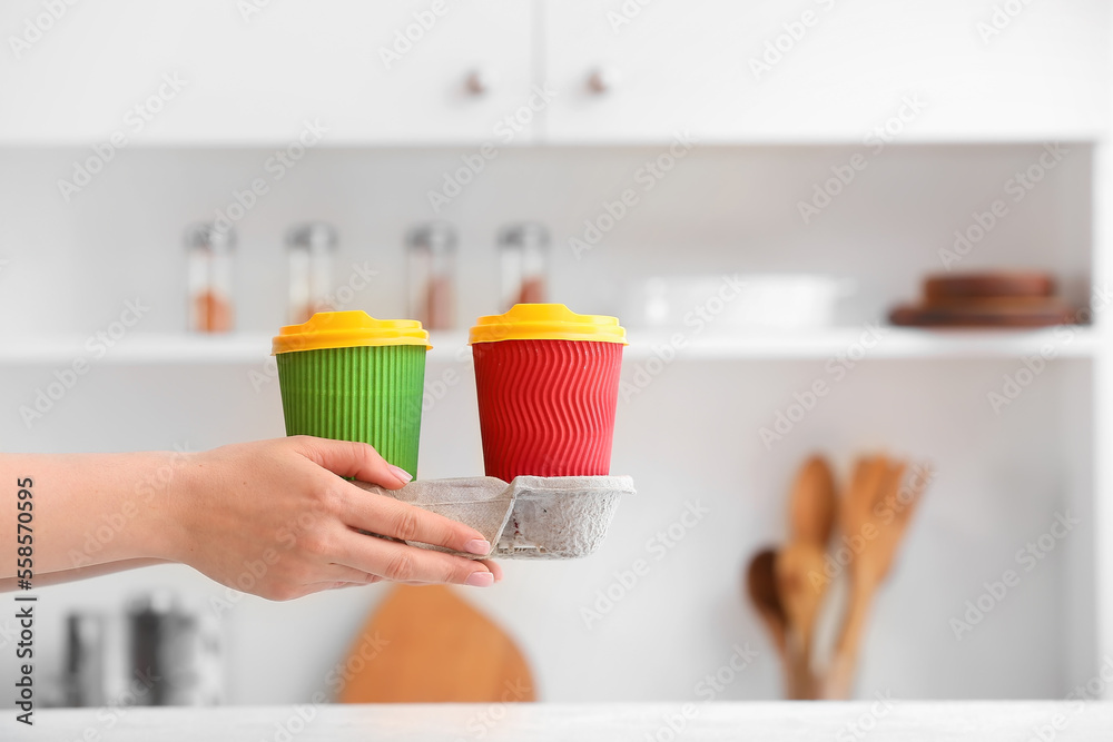 Female hand with paper cup holder on kitchen