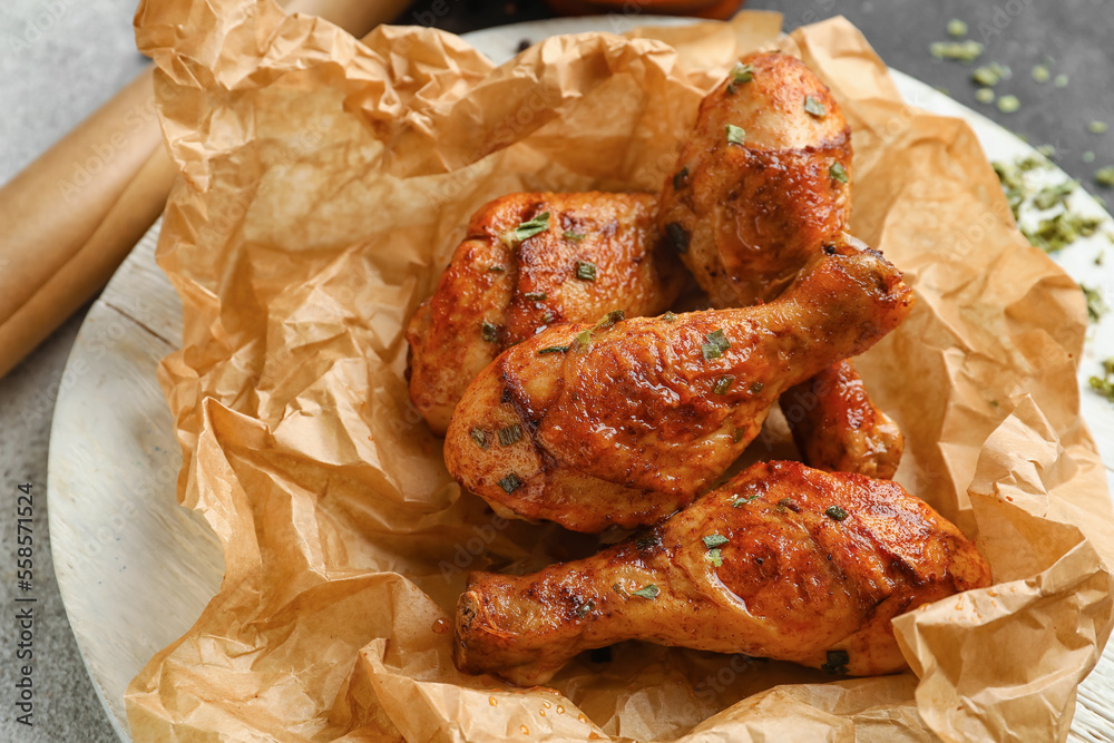 Wooden board with tasty baked chicken legs on table, closeup