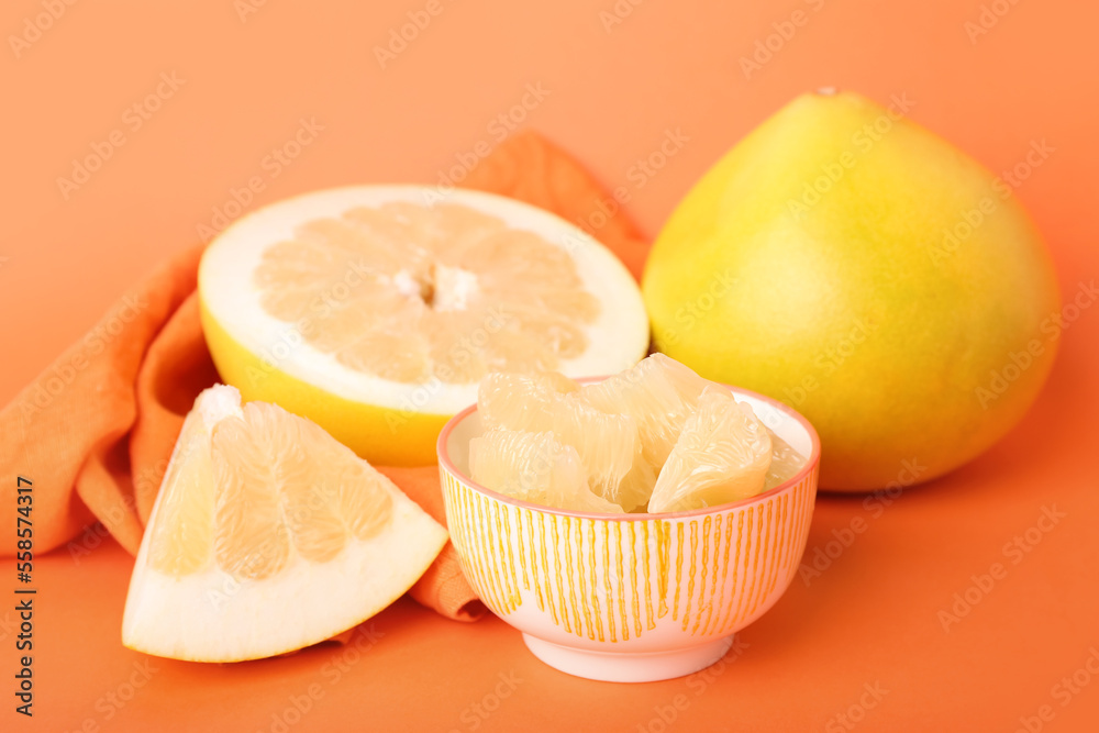 Bowl with pomelo slices on orange background