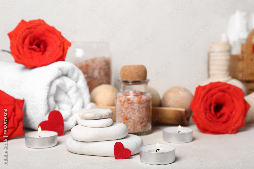 Beautiful spa composition for Valentines Day with stones, candles, sea salt, towel and rose flowers