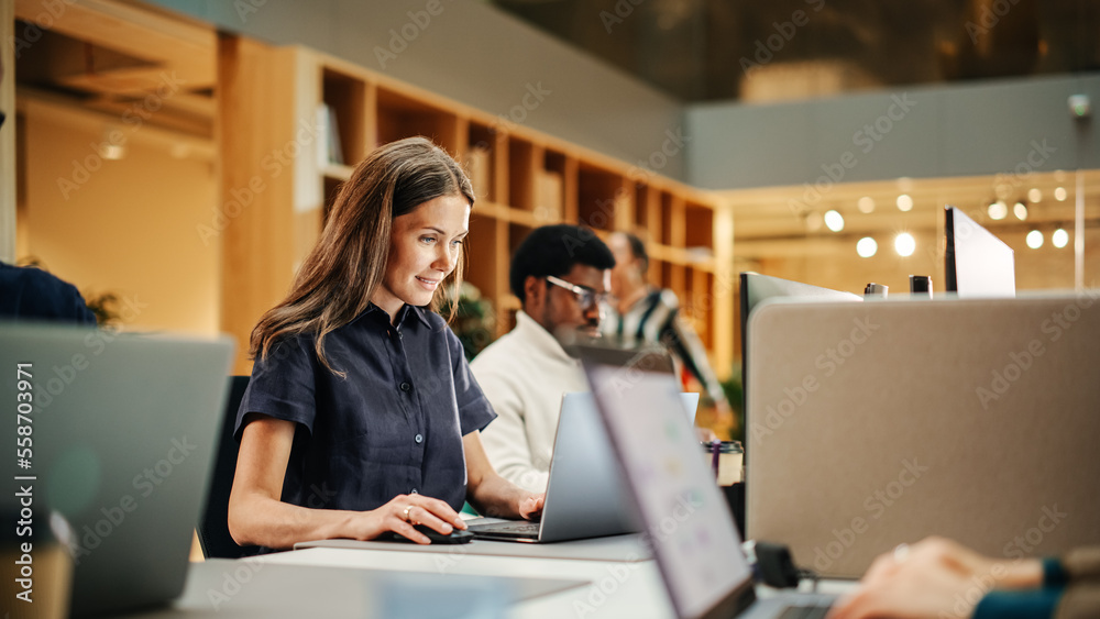 Portrait of Caucasian Inspired Young Woman Smiling and Using Laptop in Bright Contemporary Office. C