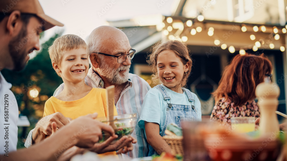 Happy Senior Grandfather Talking and Having Fun with His Grandchildren, Holding Them on Lap at a Out