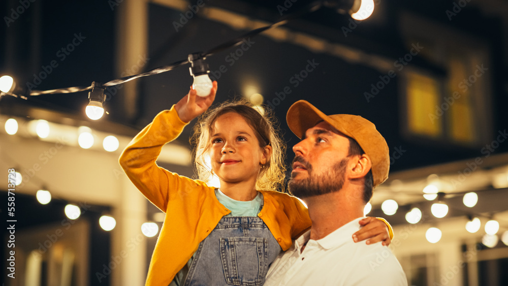 Happy Handsome Father Helping His Little Beautiful Daughter to Change a Lightbulb in Fairy Lights Ba