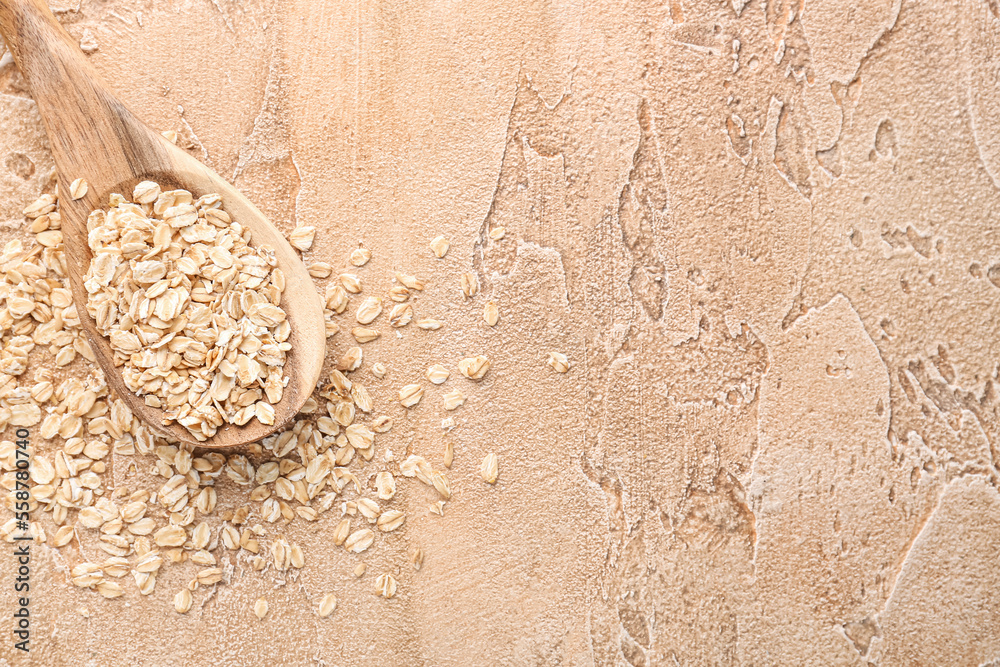 Wooden spoon with raw oatmeal on color background, closeup