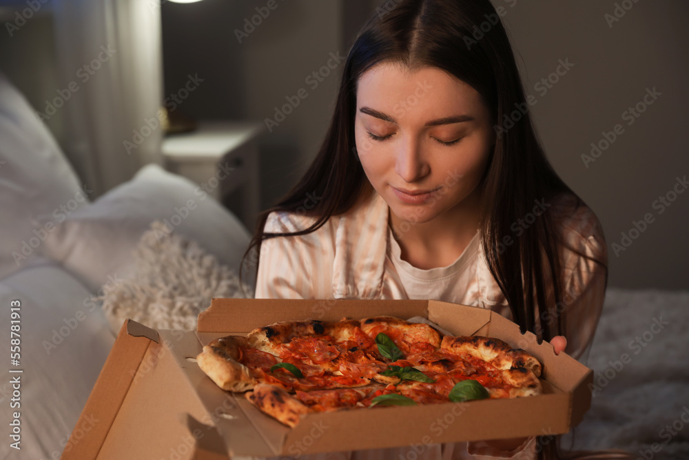 年轻女子晚上在卧室里拿着一盒美味的披萨，特写