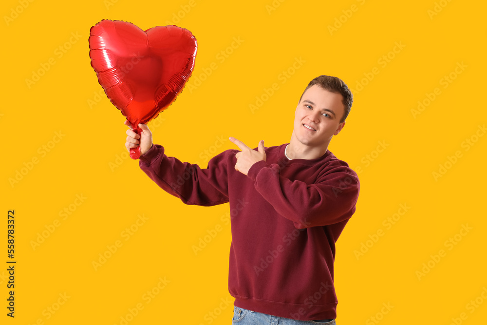 Young man with balloon for Valentines Day on yellow background