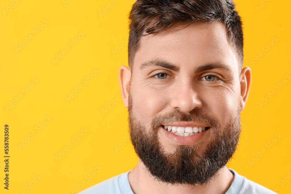 Young man with beautiful smile on yellow background, closeup