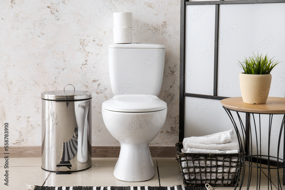 Interior of restroom with toilet bowl, table and folding screen