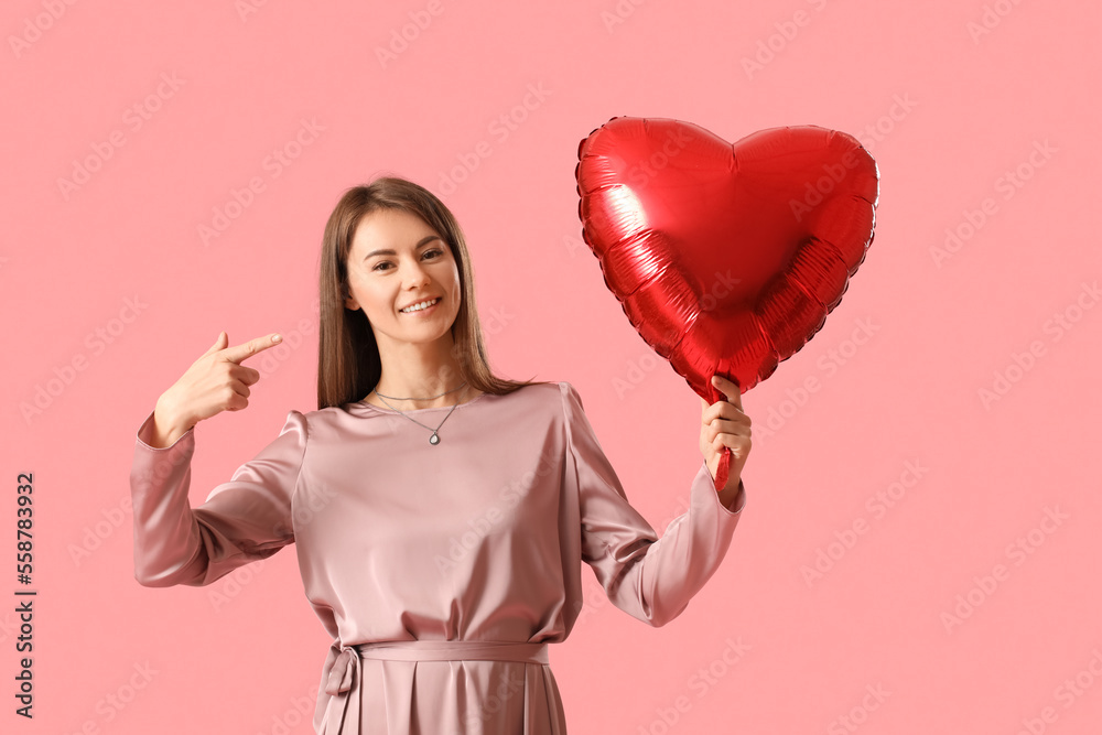 Young woman with balloon for Valentines Day on pink background