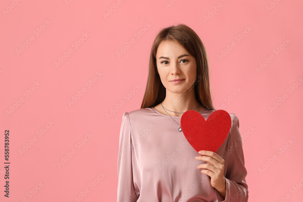 Young woman with paper heart for Valentines Day on pink background