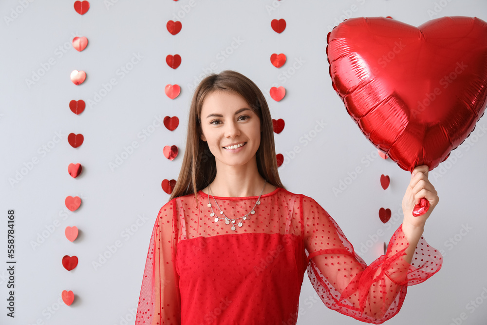 Young woman with balloon for Valentines Day on grey background