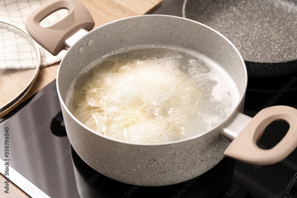 Cooking pot with boiling pasta on electric stove in kitchen