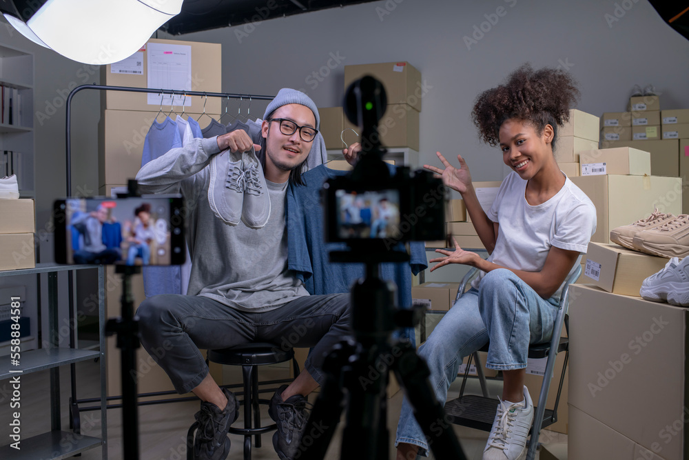 Mixed race couple of Asian man and African-American woman blogger or vlogger looking at camera revie