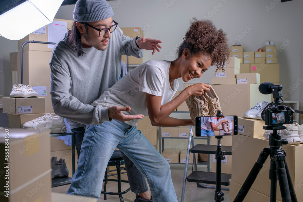 Mixed race couple of Asian man and African-American woman blogger or vlogger looking at camera revie