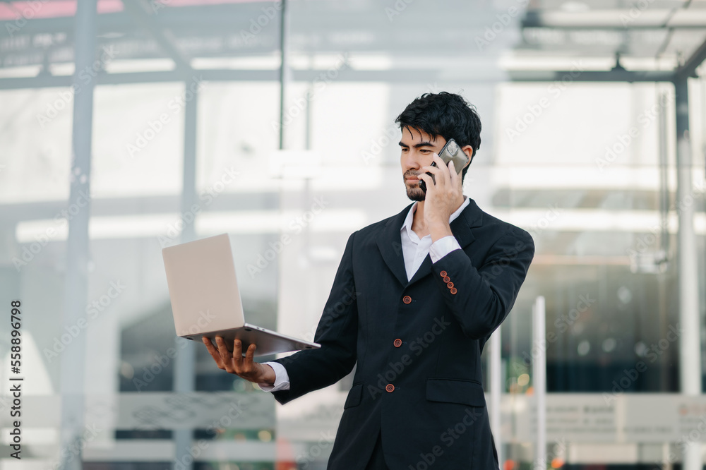 Asian Businessman sitting in the city using a cellphone and tablet, laptop.Asian Businessman sitting