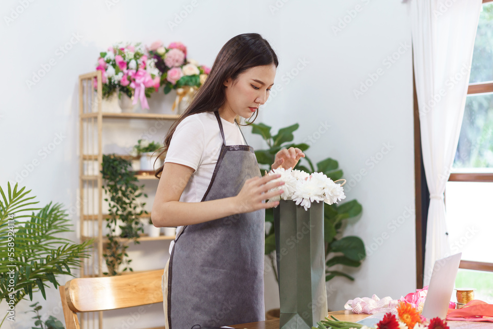 Florist concept, Female florist arranging chrysanthemum flower bouquet in shopping bag at shop