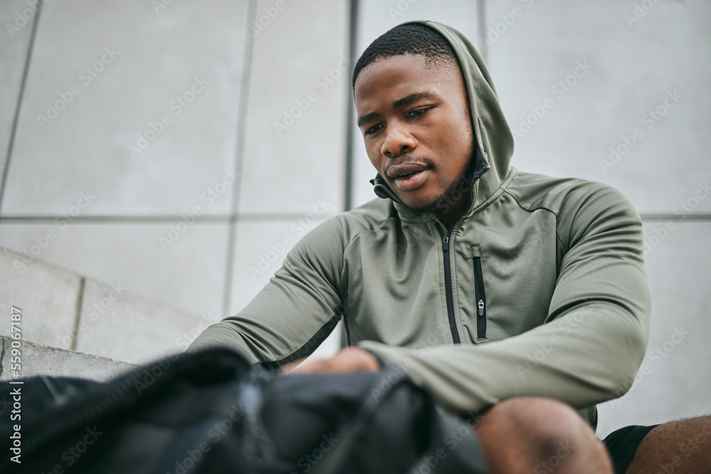 Fitness, runner and sports bag with a black man athlete taking a break from his exercise in the city