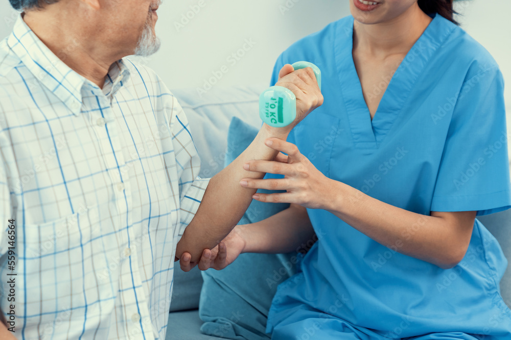 Contented senior patient doing physical therapy with the help of his caregiver. Senior physical ther