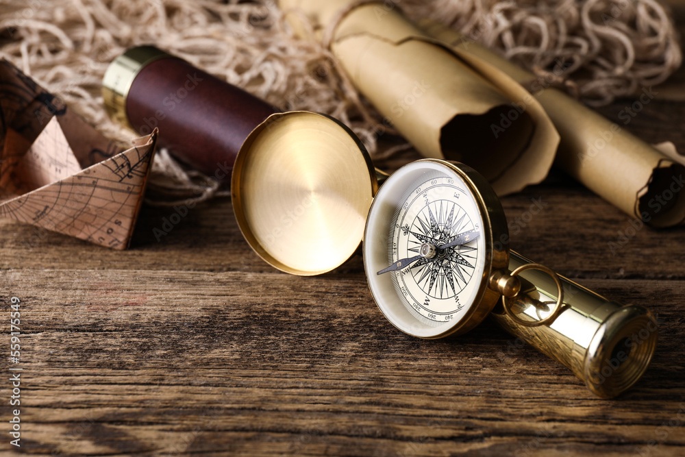 Golden compass and spyglass on dark wooden background