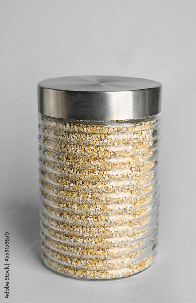 Glass jar of wheat groats on white background