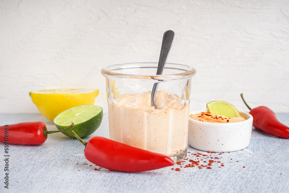 Glass of tasty chipotle sauce on light background