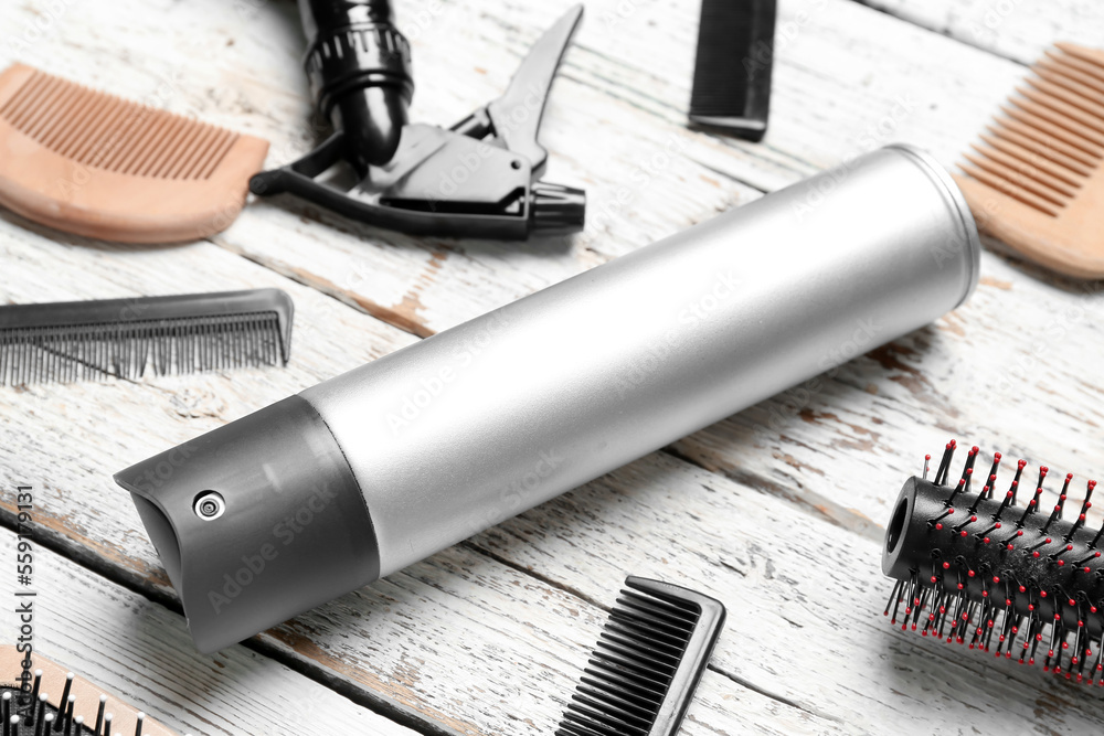 Hair spray with combs on white wooden background, closeup