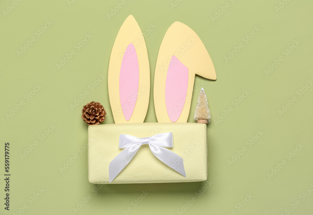 Paper bunny ears with Christmas tree, fir cone and gift on green background