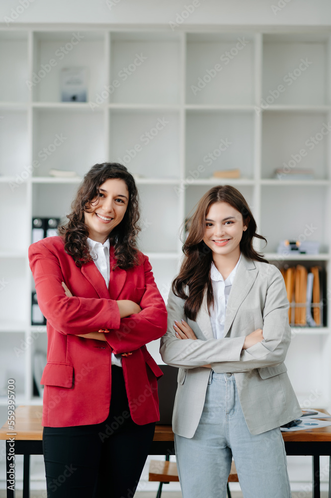 Young attractive  two female office worker business suits smiling at camera in office ..