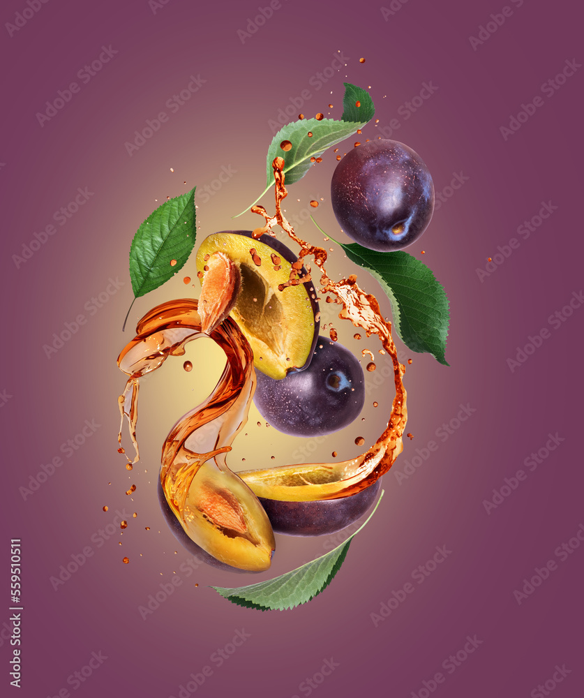 Whole and sliced plums with juice splashes in the air