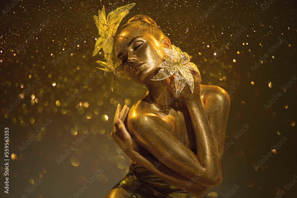 High Fashion gold model woman with bright golden sparkles on skin, fantasy flower, portrait of beaut