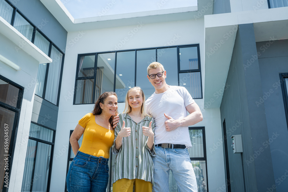 Daughter holding keys with their parent having fun together in front of their new house.