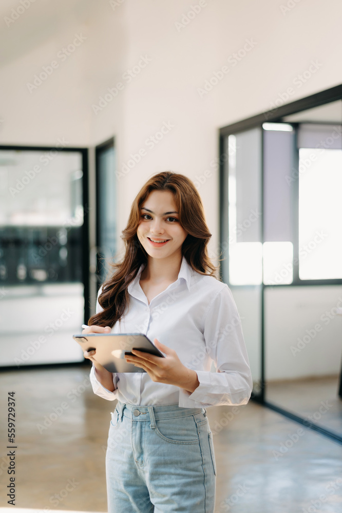 Attractive Asian female office worker business suits smiling at camera in office .