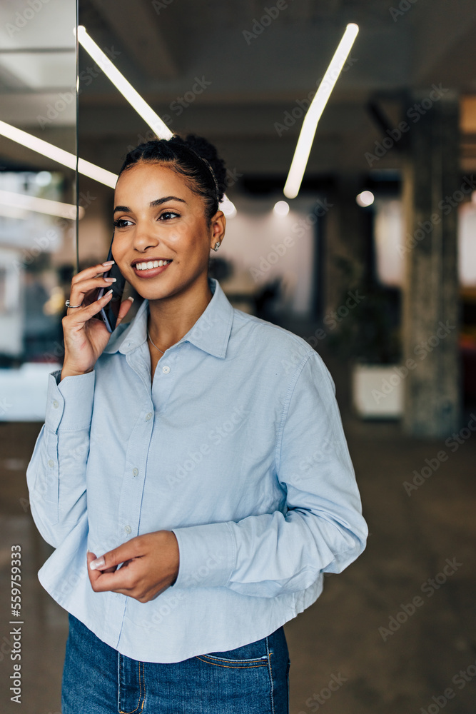 积极的非洲女人在室内，通过电话交谈。