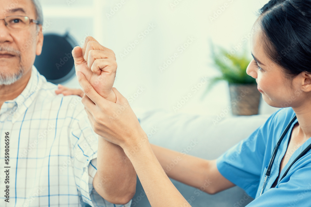 Caring young female doctor performing osteopathy treatment for a contented senior patient. At-home m