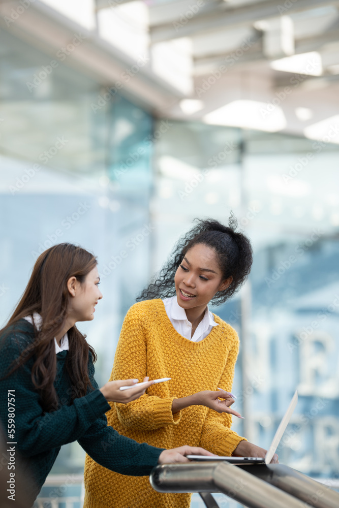 两个快乐的多民族朋友在看电脑平板电脑。不同种族年轻女性的画像