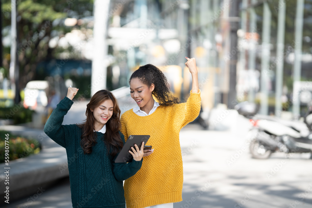 两个快乐的多民族朋友在看电脑平板电脑。不同年轻女性的画像