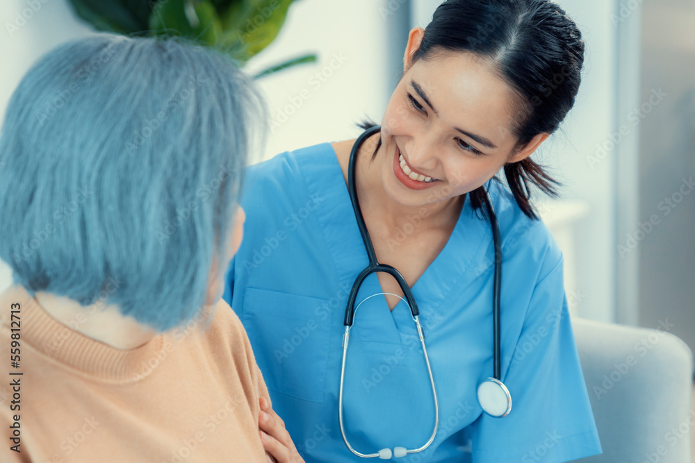 A caregiver rest her hands on the shoulders of a contented senior patient while she sitting on the s