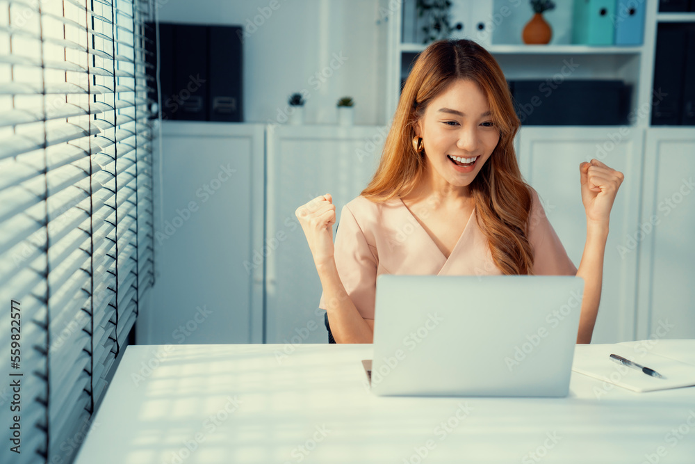 A young female employee receives a promotion, good news or finished her task and overjoyed for being