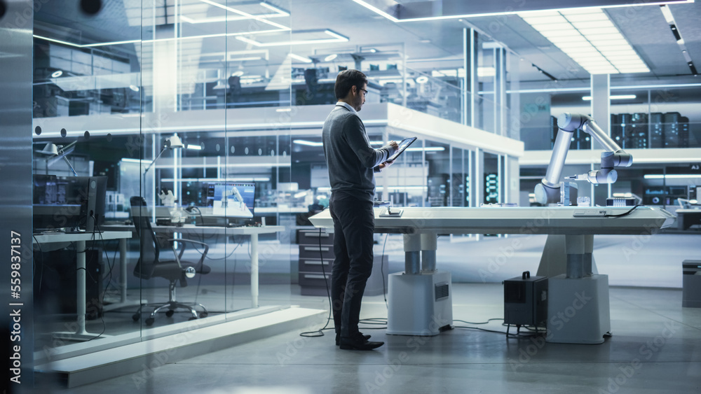 Young Multiethnic Male Engineer Using a Tablet Computer, Researching and Developing a Futuristic Rob