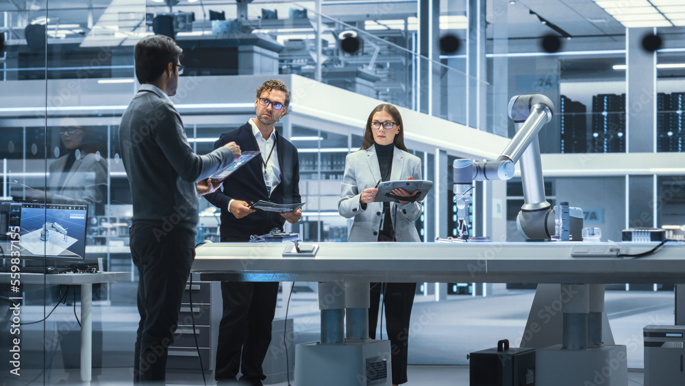 Diverse Team of Industrial Robotics Engineers Gathered Around a Table With Robotic Arm. Scientists U