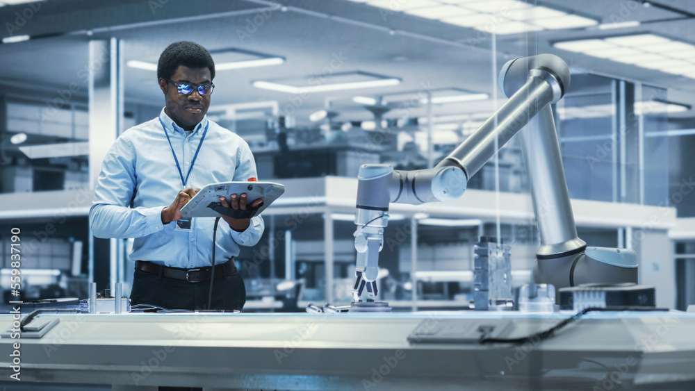 Young Black Male Engineer Using a Tablet Computer, Researching and Developing a Futuristic Robotic A