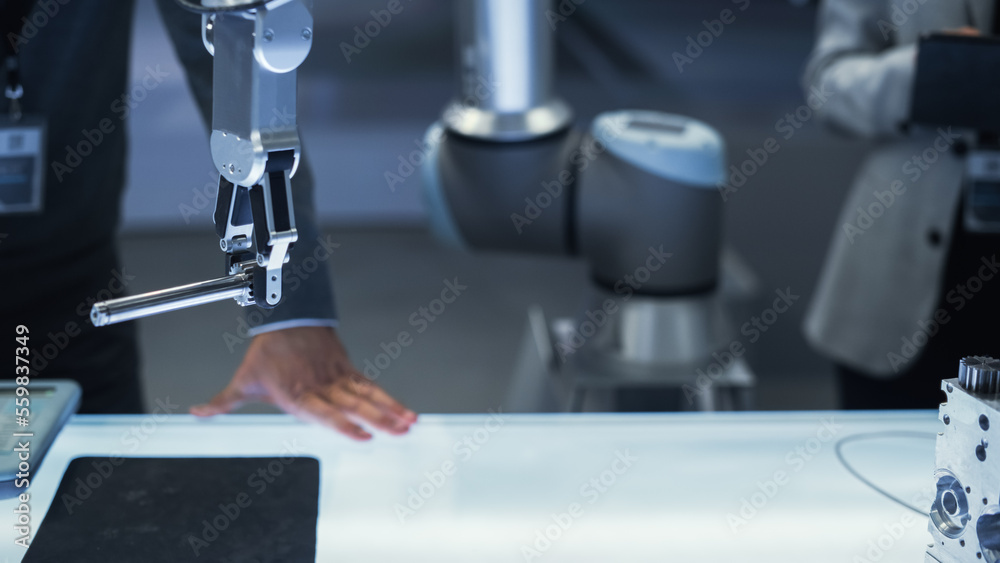 Close Up Shot of a Modern Robotic Arm Holding and Moving a Mechanical Metal Component. Diverse Team 