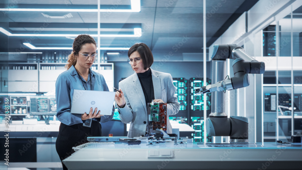 Two Female Working in High Tech Facility. Robotics Engineer and Machinery Operator Collaborate on a 